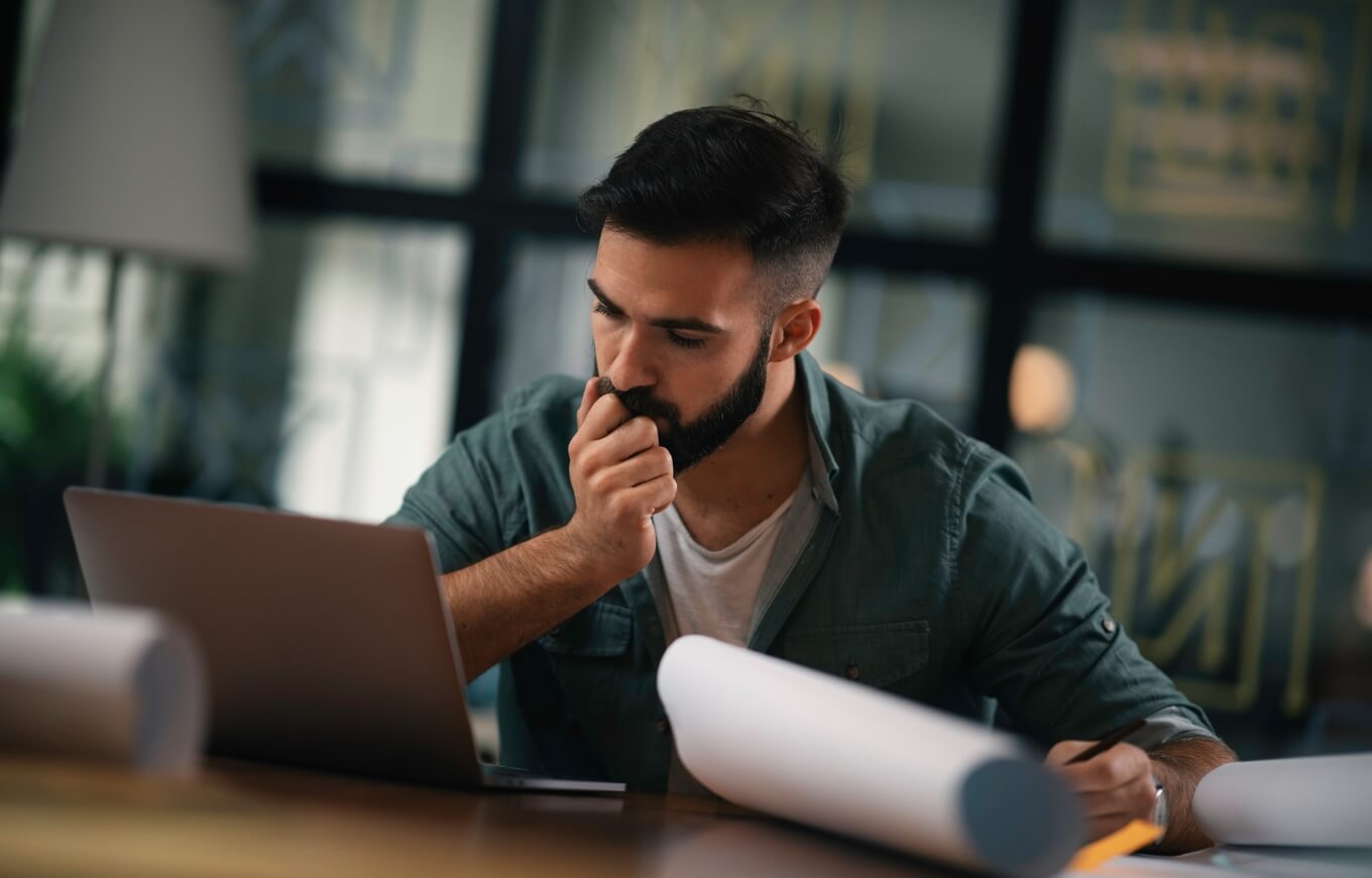 A man taking notes at his laptop.